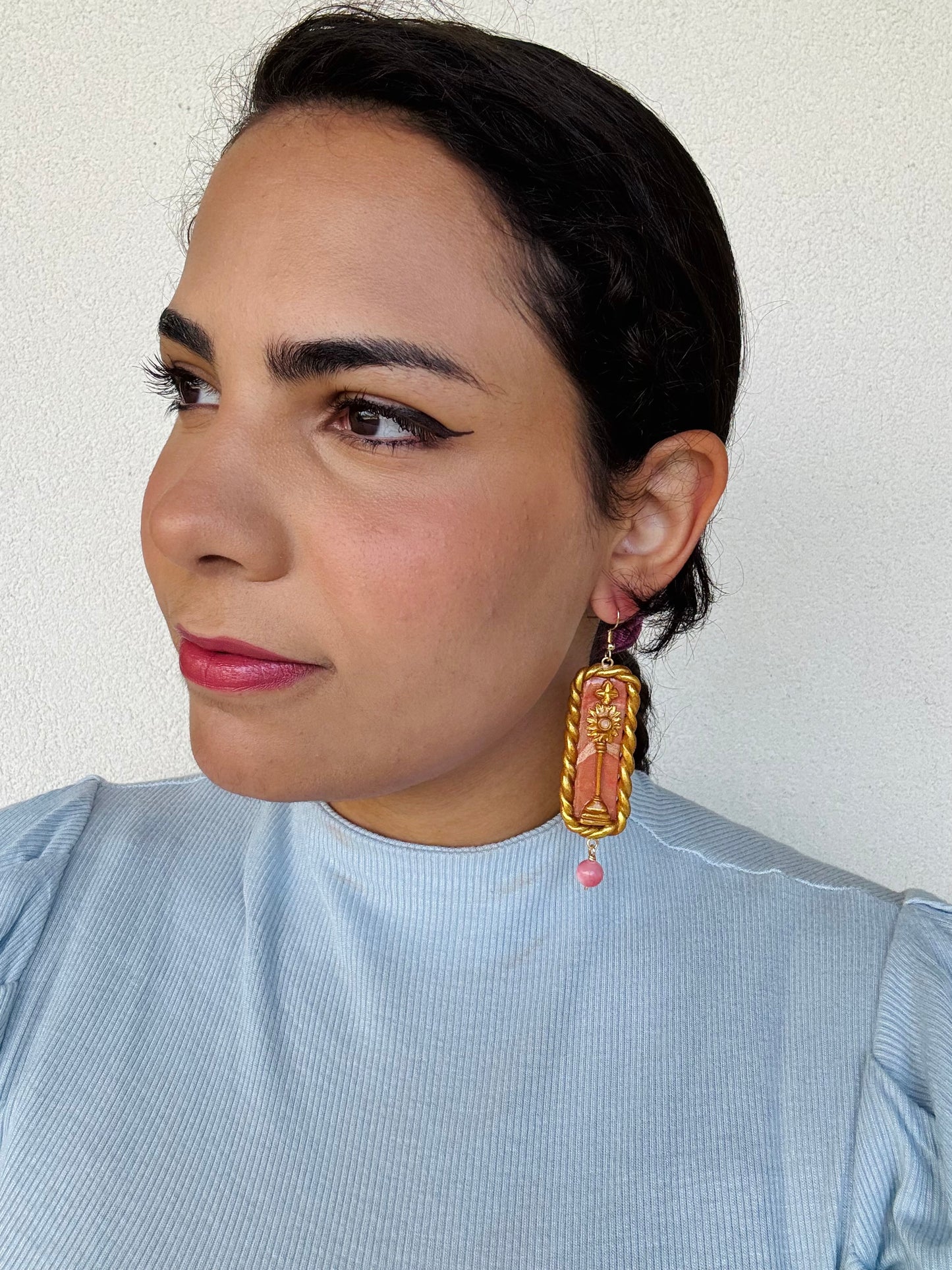 Woman in blue top wearing Monstrance earrings